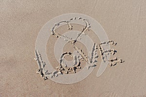 Drawn heart symbol and word love written in beach sand