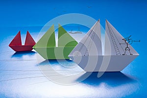 Drawn man looking through spyglass on Paper Boat Sailing with other on Blue paper sea with Drawn Details. Origami Ship