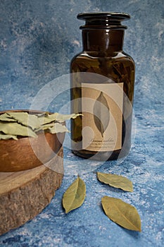 Dray Laurus nobilis Leafs in a wooden plate and dark botanic glass bottle