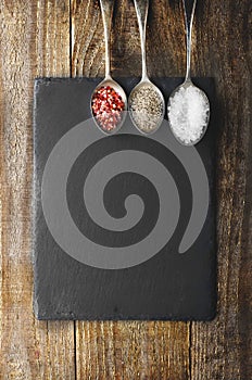 Dray spices on metal spoon on black stone with copy space. Wood