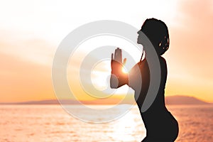 A dreadful girl with a beautiful figure meditates at sunset on the sea