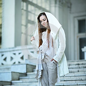 Dreadlocks fashionable girl posing near old white house