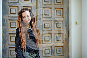 Dreadlocks fashionable girl posing at old wooden door background