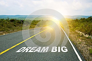 Dream big, concept photo of asphalt road. Motivational inscription on the road going forward. The beginning of a new path. A