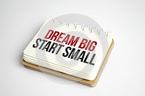 dream big start small words on white notebook and grey cat