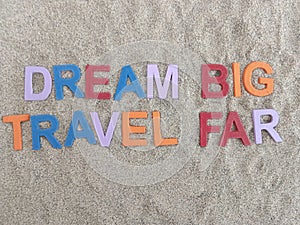 Dream big travel far written on sand at the beach