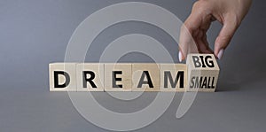 Dream Big vs Small symbol. Businessman Hand turns cubes and changes words Dream Small to Dream Big. Beautiful grey background.