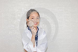 Dream careers concept, Portrait of Happy kid in science coat with magnifying glass on blurred background