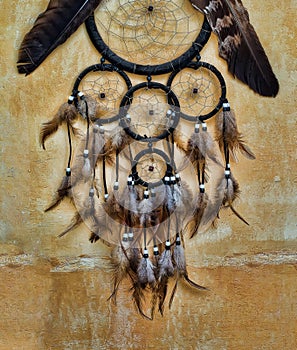 Dream catcher with eagle and raven feathers on orange structure wall