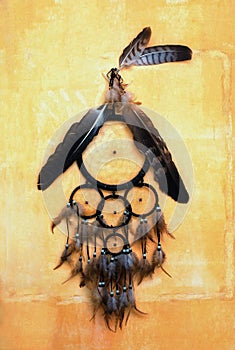 Dream catcher with eagle and raven feathers on orange structure wall