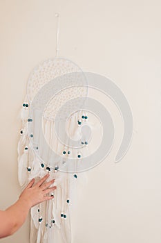Dream Catcher with white feathers and blue beads.Childrens hands hang the dream catcher. Macrame wall decoration