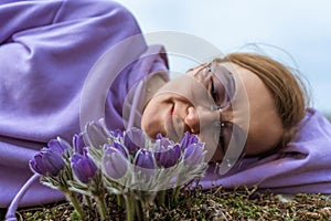 Dream grass woman spring flower. Woman lies on the ground and hugs flowers pasqueflower or Pulsatilla Grandis flowers