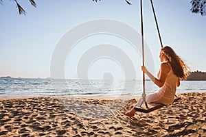 Dream and happiness concept, romantic beautiful carefree woman relaxing on the swing at sunset