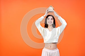 Dream of a house. Own home concept. Cheerful woman holding a little toy house above her head.