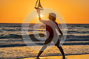 Dream of summer. Little blonde boy put toy boat in the sea waves at the beach. Summer with kids vacation. Dream on