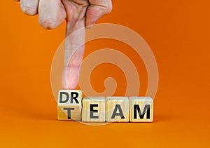 Dream team dreamteam symbol. Businessman turns wooden cubes and changes the word Dream to Team. Beautiful orange table orange