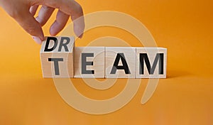 Dream Team symbol. Businessman hand turns wooden cube and changes word Team to Dream. Beautiful orange background. Business and