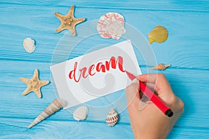 Dream text. Font of lettering motivational word on white canvas with red ink by calligrapher. Seashells and sea stars