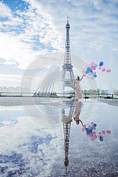 Dream travel - young woman with balloons walking near Eiffel Tower in Paris