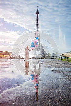 Dream travel - young woman with balloons walking near Eiffel Tower in Paris