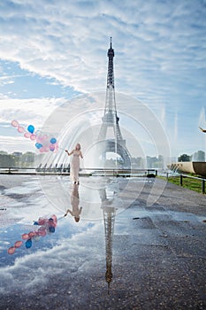 Dream travel - young woman with balloons walking near Eiffel Tower in Paris