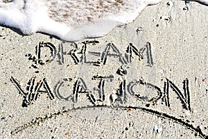 Dream vacation phrase handwritten on the beach