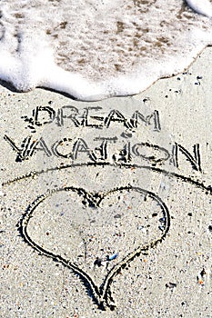 Dream vacation phrase handwritten on the sandy beach