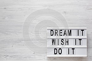 `Dream it, wish it, do it` words on a lightbox on a white wooden background, top view. Overhead, from above, flat lay. Copy spac