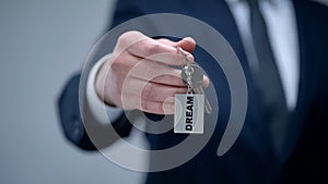 Dream word on keychain in businessman hand, mindset to goal achievement, closeup