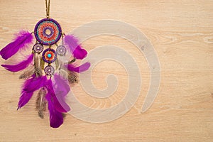 Dreamcather with purple feathers on the light wooden background