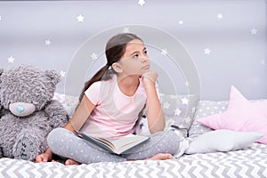 Dreamer concept. Cute little dreamer. Dreamer girl dream in bed. Child dreamer with book and teddy bear. Childhood dream