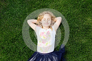 Dreaming adorable girl lying on grass, top view