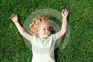 Dreaming adorable little girl lying on grass