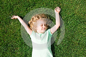 Dreaming adorable little girl lying on grass