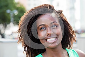 Dreaming african american woman in a green shirt outdoor