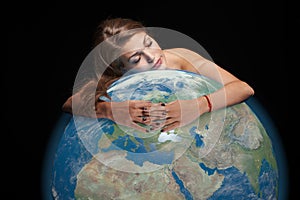 Dreaming beautiful woman hugging earth globe in her hands with closed eyes