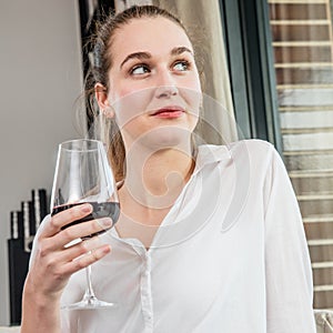 Dreaming beautiful young woman enjoying holding wine glass for degustation photo