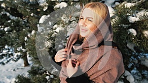 Dreaming blond woman looks far away in winter pine forest outside