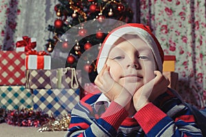 Dreaming boy in front of the christmas tree