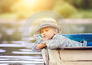 Dreaming boy lying in old boat on the river