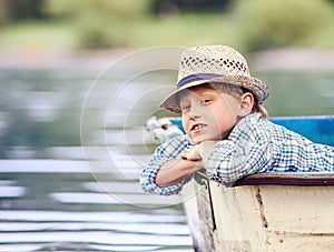 Dreaming boy lying in old boat on the river