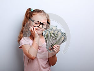 Dreaming cute kid girl looking on money and thinking how can spend