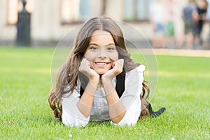 Dreaming of future. Happy girl relax on green grass. Small child with cute smile. Future generation. Future of education