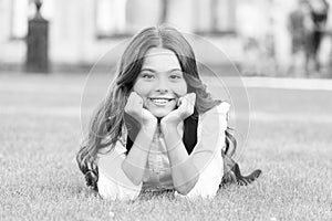 Dreaming of future. Happy girl relax on green grass. Small child with cute smile. Future generation. Future of education