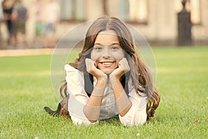 Dreaming of future. Happy girl relax on green grass. Small child with cute smile. Future generation. Future of education