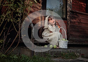 Dreaming girl with apples on a summer evening near the old house