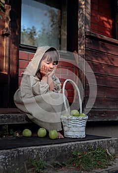 Dreaming girl with apples on a summer evening near the old house