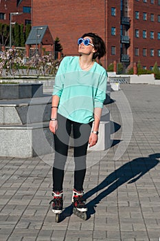 Dreaming girl in a funny sunglasses roller skating in the park