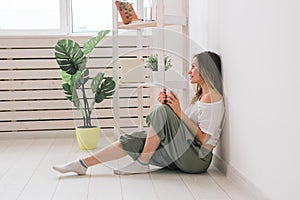 Dreaming girl sitting on floor at home and drink tea from cup.