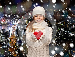 Dreaming girl in winter clothes with red heart